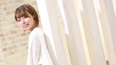  短い茶色の髪をした笑顔の女性が肩越しにちらっと見えます。