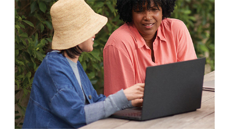 ノート PC を操作しながら話す 2 人の人物