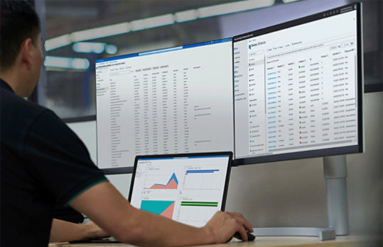 大型 PC でラップトップで作業する男性