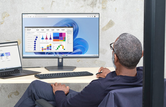 デスクトップとラップトップで作業している男