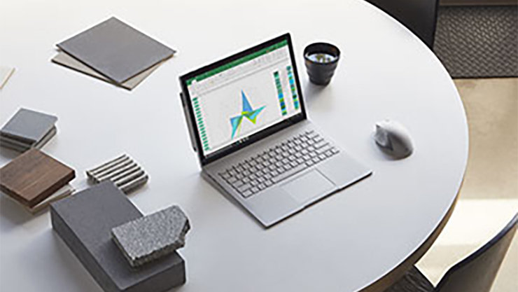 本、コーヒーカップ、マウスを備えたテーブルにあるオープンサーフェスのラップトップ。