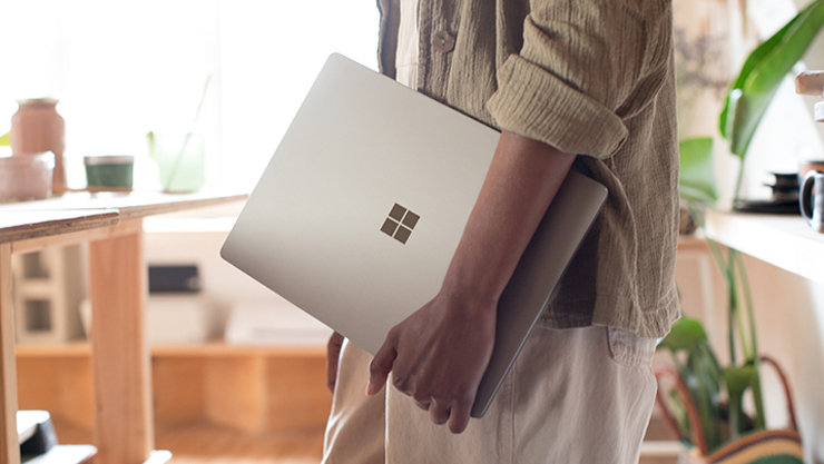 人は彼の手でWindowsラップトップを持って歩いています   