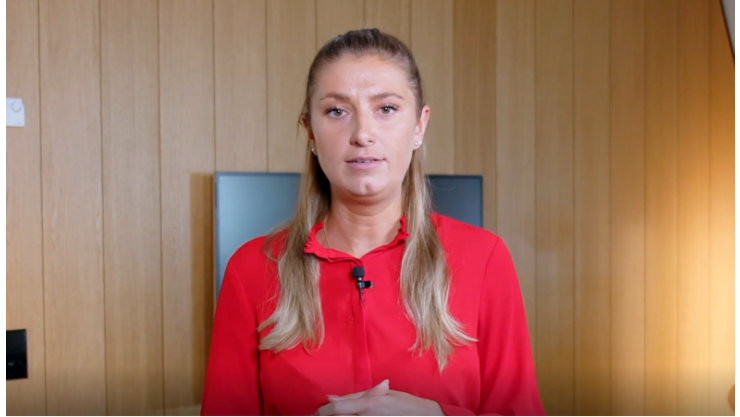 Frau vor Holzwand in hellem Raum.