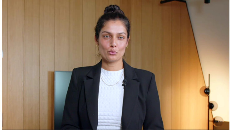 Frau vor Holzwand in hellem Raum.