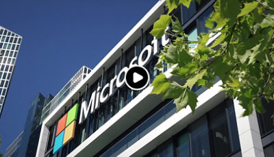 Bürogebäude mit Microsoft Logo, im Hintergrund blauer Himmel