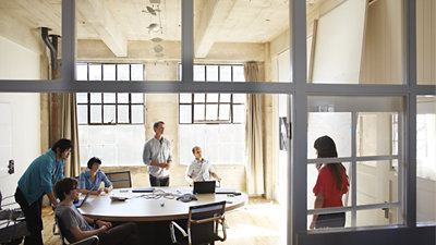 丸いテーブルが置かれた明るいミーティング ルームで会議をする 6 人のビジネス パーソン