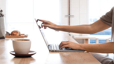 ノート PC の画面にタッチ入力をする人物