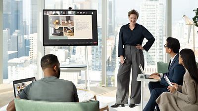 Surface Hub を使用して他の 3 人にプレゼンテーションを行うビジネスパーソン