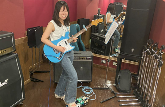 ベースの楽器を弾いているTomomi