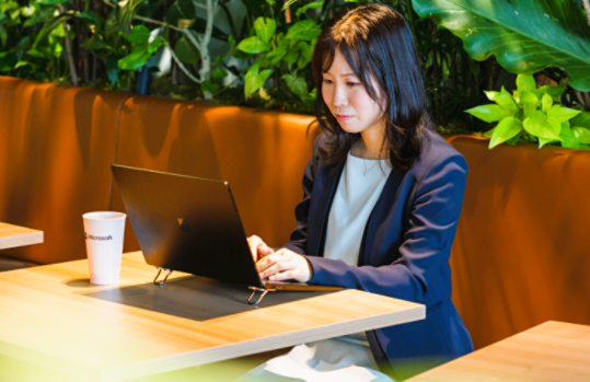 観葉植物が背景にある室内でパソコンに向かって作業をしているTomomi