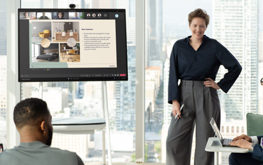 Surface Hub を使用して他の 3 人にプレゼンテーションを行うビジネスパーソン