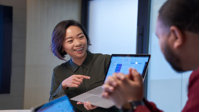 女性がノートパソコンで向かいに座っている男性に何かを説明している