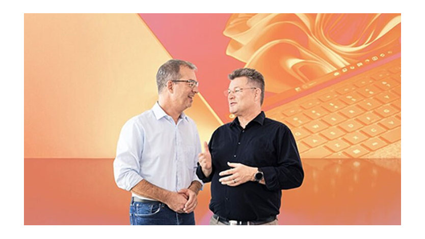 Zwei Männer unterhalten sich vor abstraktem, orangefarbenem Hintergrund, der einen Laptop darstellt.