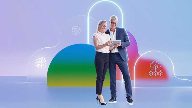 Ein Mann und eine Frau stehen vor violettem Hintergrund, die Frau hält einen Laptop in den Händen.