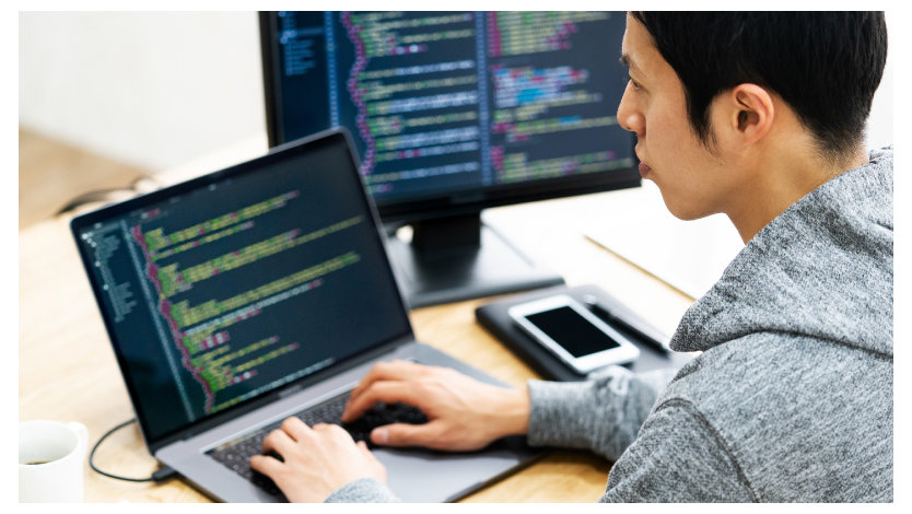 ノート PC でプログラミングを行う男性