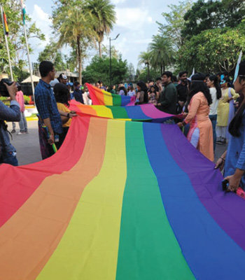 A group of people hold a large rainbow flag