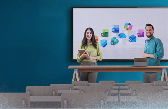 Zwei Personen stehen in einem Hörsaal vor einem Bildschirm mit Microsoft‑365‑App‑Icons.