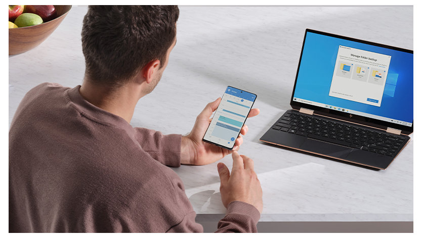 テーブルのノート PC とスマートフォンと操作する人物