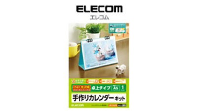 机の上に置かれた青い卓上カレンダーのサンプルと緑のブランド表示が載ったELECOM A5横型卓上カレンダーキットのパッケージ。