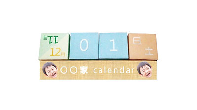 パステルカラーの数字と曜日のキューブを木製台に並べ、両端に子どもの顔を配置した万年サイコロカレンダー。