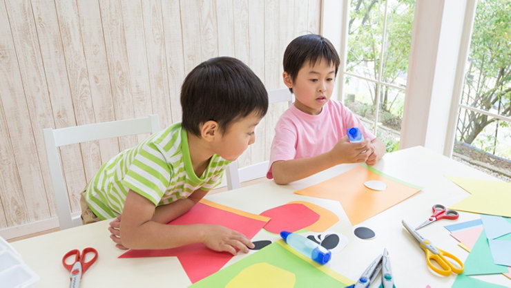 2人の男の子がテーブルの上でアートクラフトを作るために遊んでいます