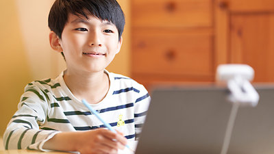 ノート PC の画面を見ながら勉強をする小学生