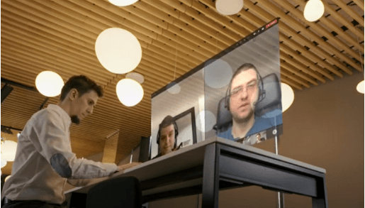 Mężczyzna pracuje przy biurku na laptopie, obok zrzut z jego monitora z dwoma uczestnikami spotkania na Teams