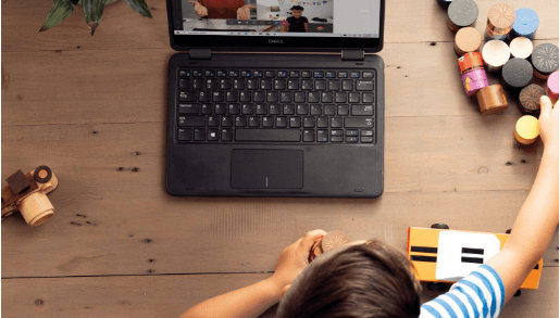 Dziecko siedzi przy biurku, bawi się klockami i uczestniczy w rozmowie na Microsoft Teams