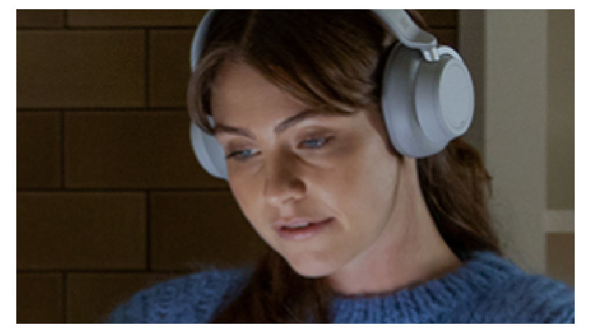 Kobieta z założonymi słuchawkami przed laptopem
