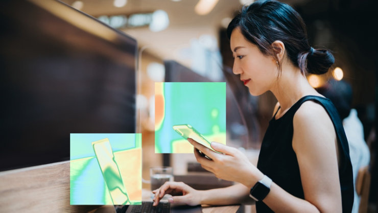 カラフルな抽象的なオーバーレイが表示されている机の上でスマートフォンとノートパソコンを使用している人