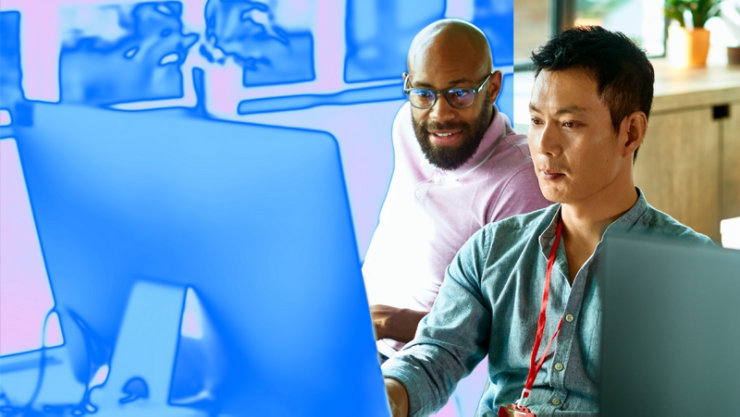 オフィスでコンピューターを使って共同作業をする2人。