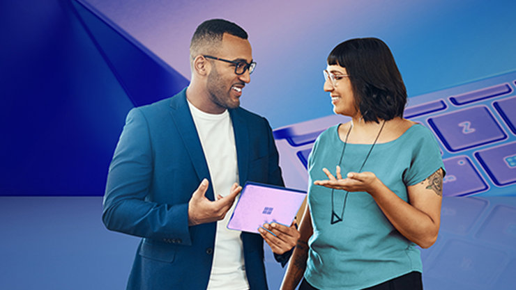 Eine Frau und ein Mann unterhalten sich, die Frau hält ein Tablet. Im Hintergrund ist eine Tastatur zu sehen.