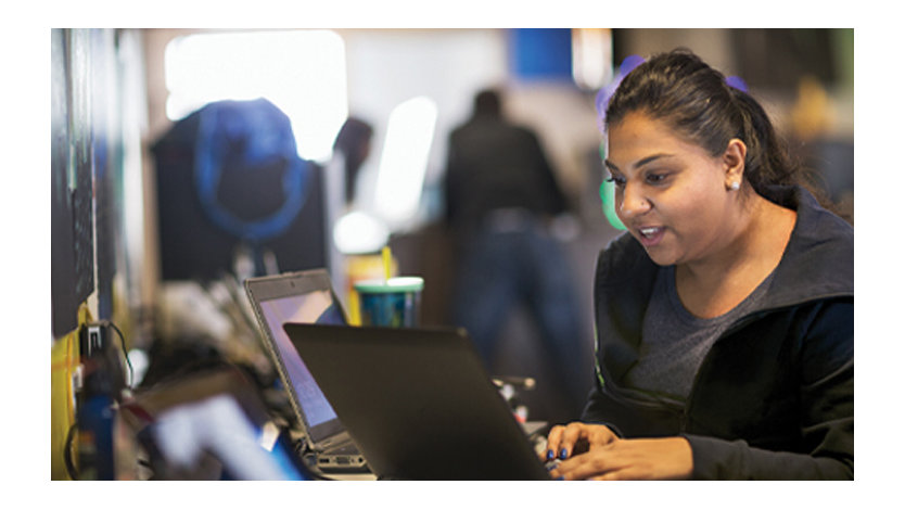 A woman working on two laptops