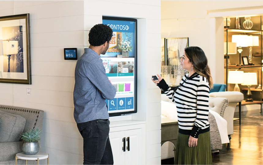 Two customers looking at an interactive screen in a furniture retail shop