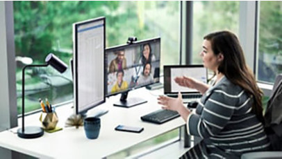 Female enterprise employee working at desk with multiple devices