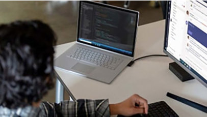 Commercial contextual lifestyle image of adult male at desk workstation on Surface Book 3 in Microsoft Azure and Microsoft Teams.