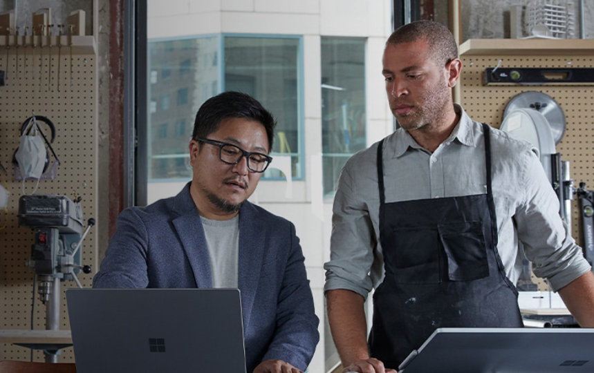 Two male staff in discussion in store using laptop
