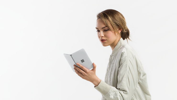 白い服を着た女の人が、Surface Duo 2 の画面を見ている様子