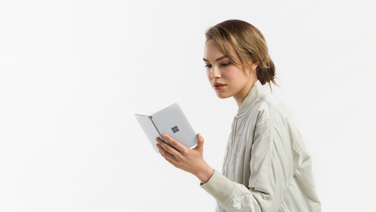 白い服を着た女の人が、Surface Duo 2 の画面を見ている様子