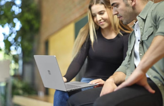 A woman and a man looking at a Surface laptop.