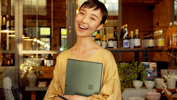 Surface デバイスを持ち、カフェで微笑む女性