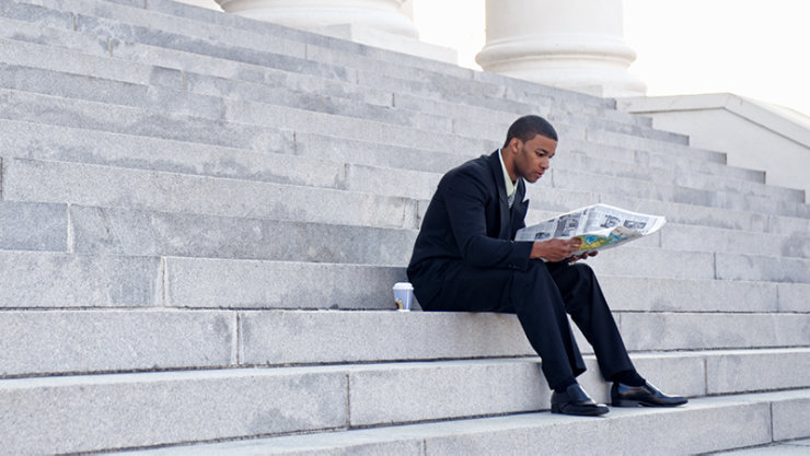 A man sitting on the stairs and reading newpaper