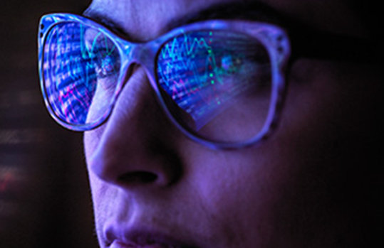 Zoomed in photo of a woman wearing glasses with a computer screen reflected in her lenses