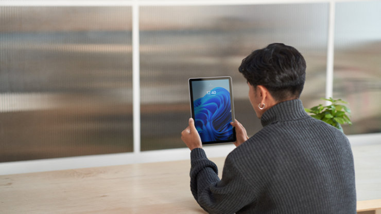 タブレットを両手で顔の前に持ち、顔認証ででサイン インする人物
