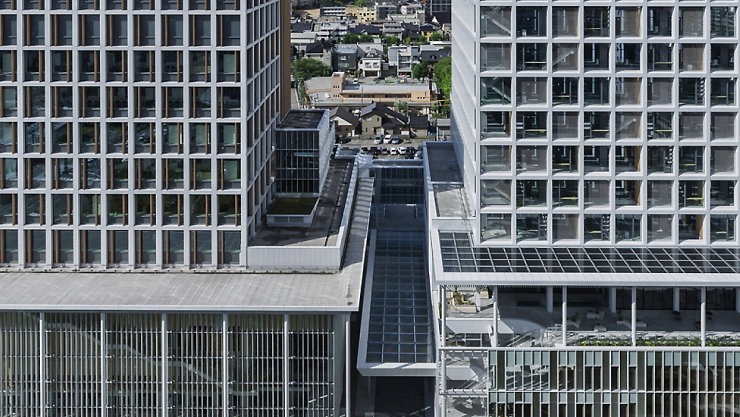  中央にスカイブリッジがあり、2つの近代的な高層ビルの間から市街地が見える景色。