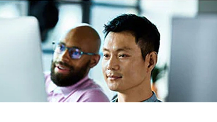 남자 두 명이 모니터를 보고 있다.