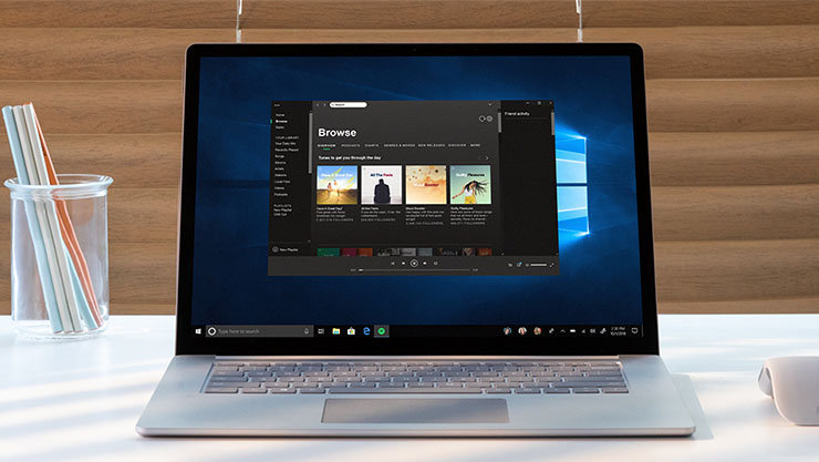 机の上のシルバーのノートパソコンで、音楽ストリーミングサービスが開いています。