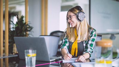 A girl watching the laptop and take the notes