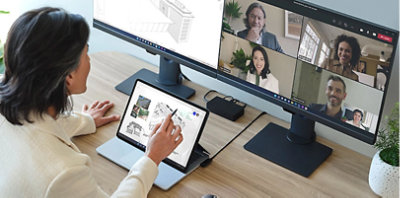 A person sitting at a desk participating in a Teams video call and viewing architectural designs