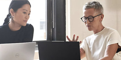 Two people having a conversation and looking at laptops